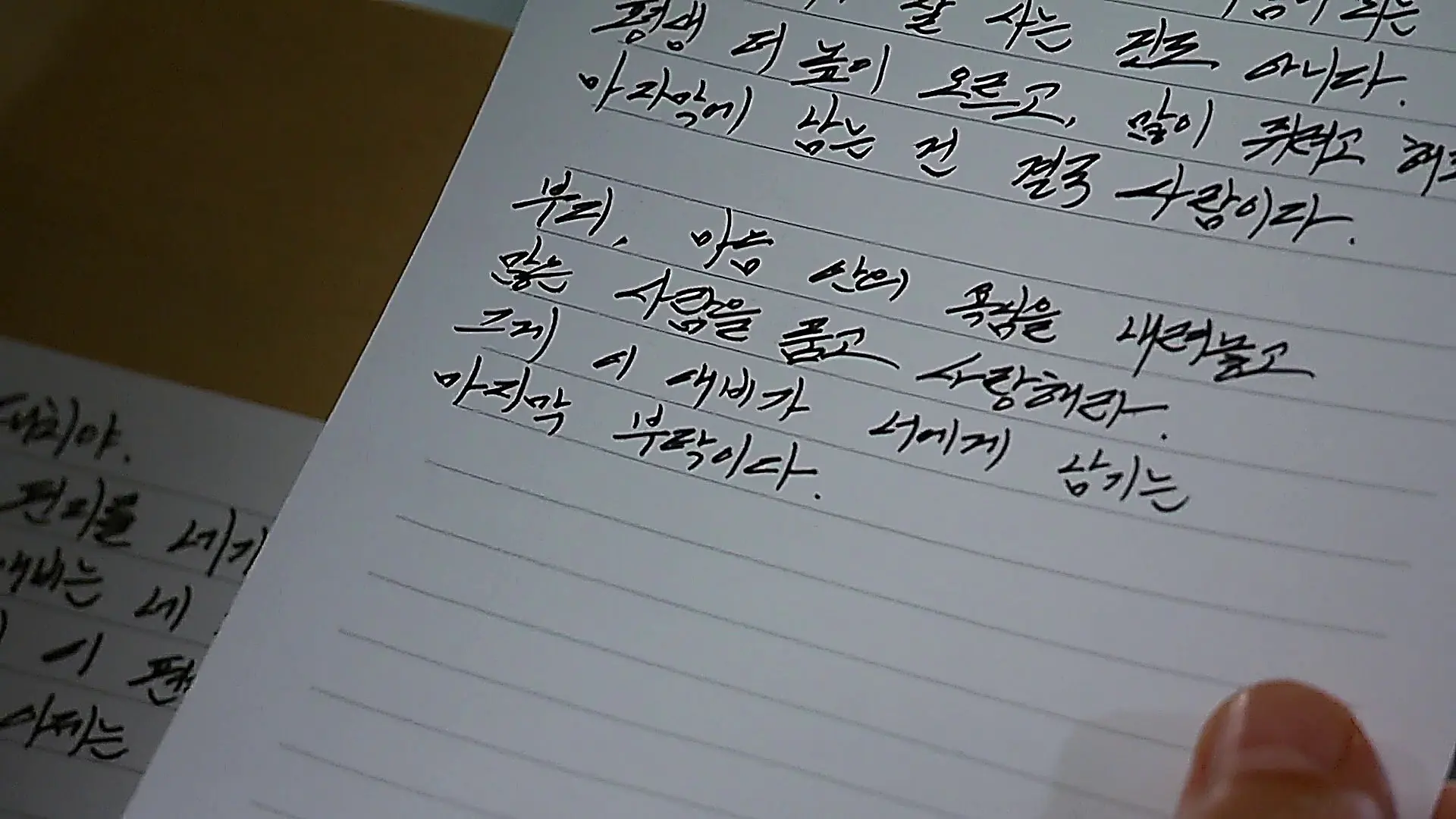 便箋に手書きの文字が記された書面とそれを持つ指先