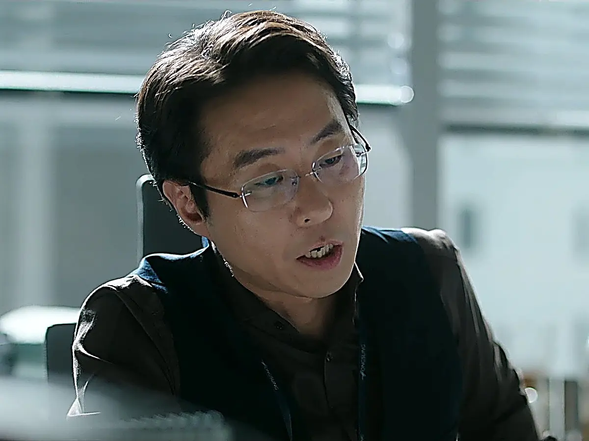 眼鏡をかけて机に向かい話す男性