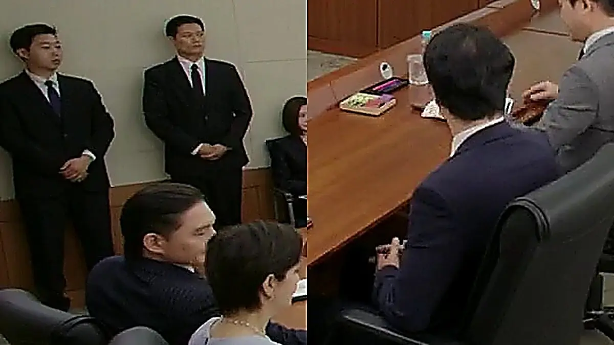 会議室の長いテーブルを囲んで着席するスーツ姿の人々