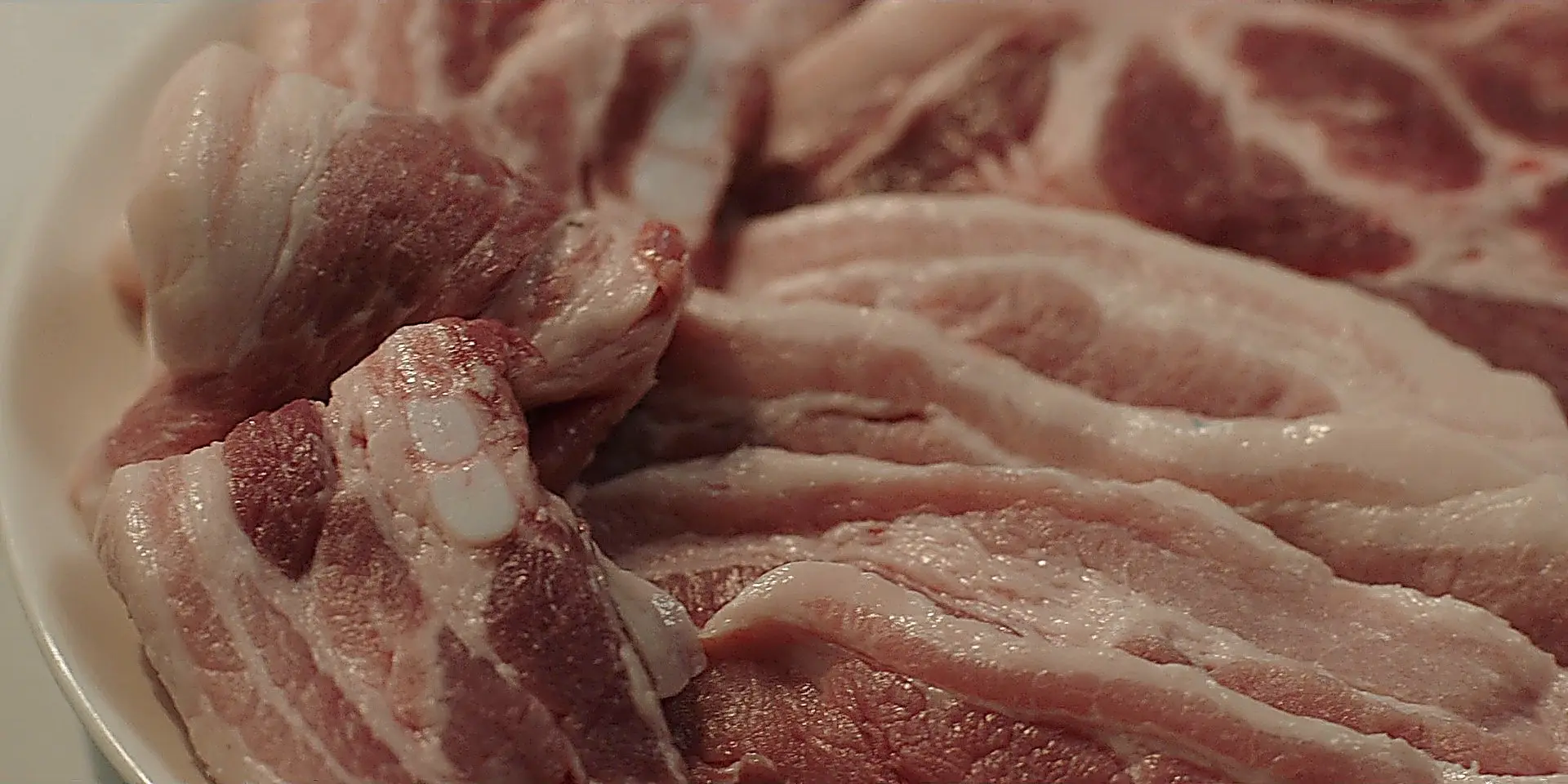 白の平皿に盛り付けられた生の豚バラ肉