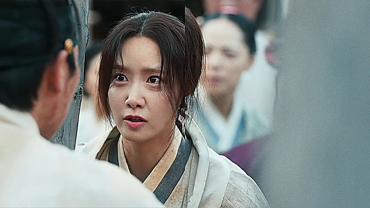 素朴な装束で木枠の間から驚いたように見つめる女性の顔