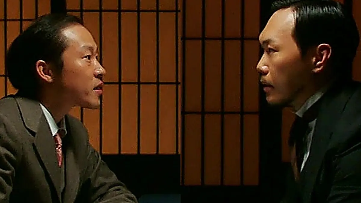 格子戸の前で向かい合って言葉を交わすスーツ姿のふたりの男性