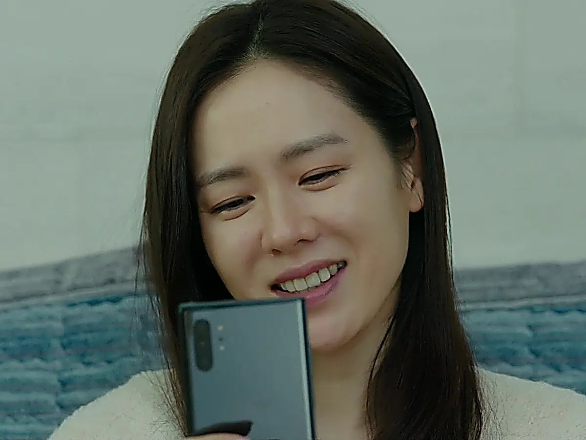 スマートフォンを手に持ち微笑む女性